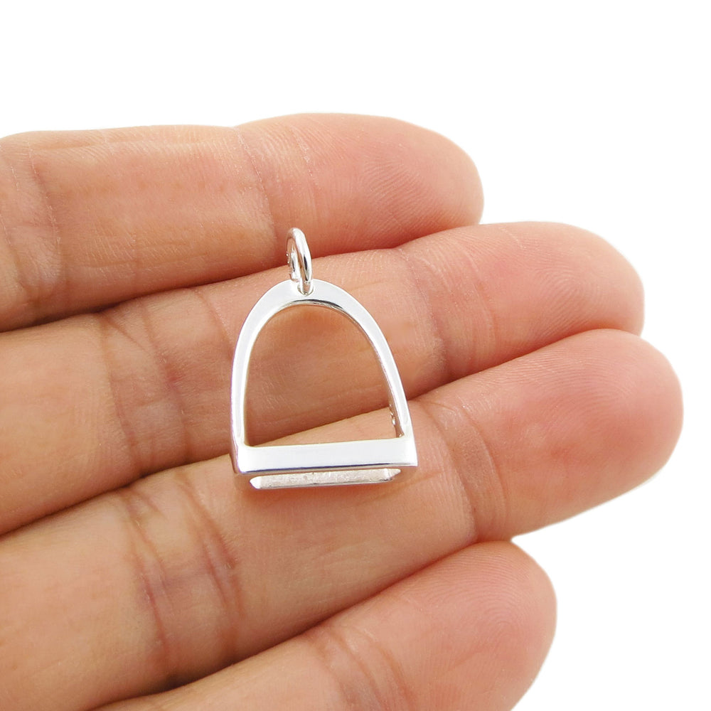 A large sterling 925 silver equestrian design pendant jewellery in the shape of a horse stirrup held in a woman's hand