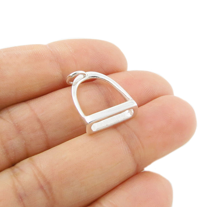 A large horse stirrup pendant jewellery in 925 held in a person's hand. 