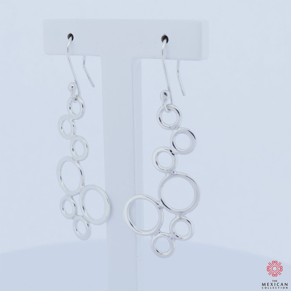 Pair of 925 sterling silver bubble dangling earring revolving on an earring stand against a white background.  