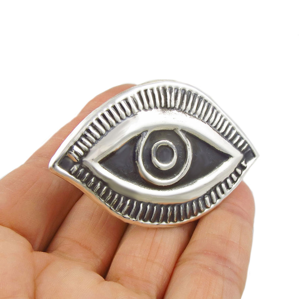 Large evil eye sterling silver cocktail ring held in a person's hand. 