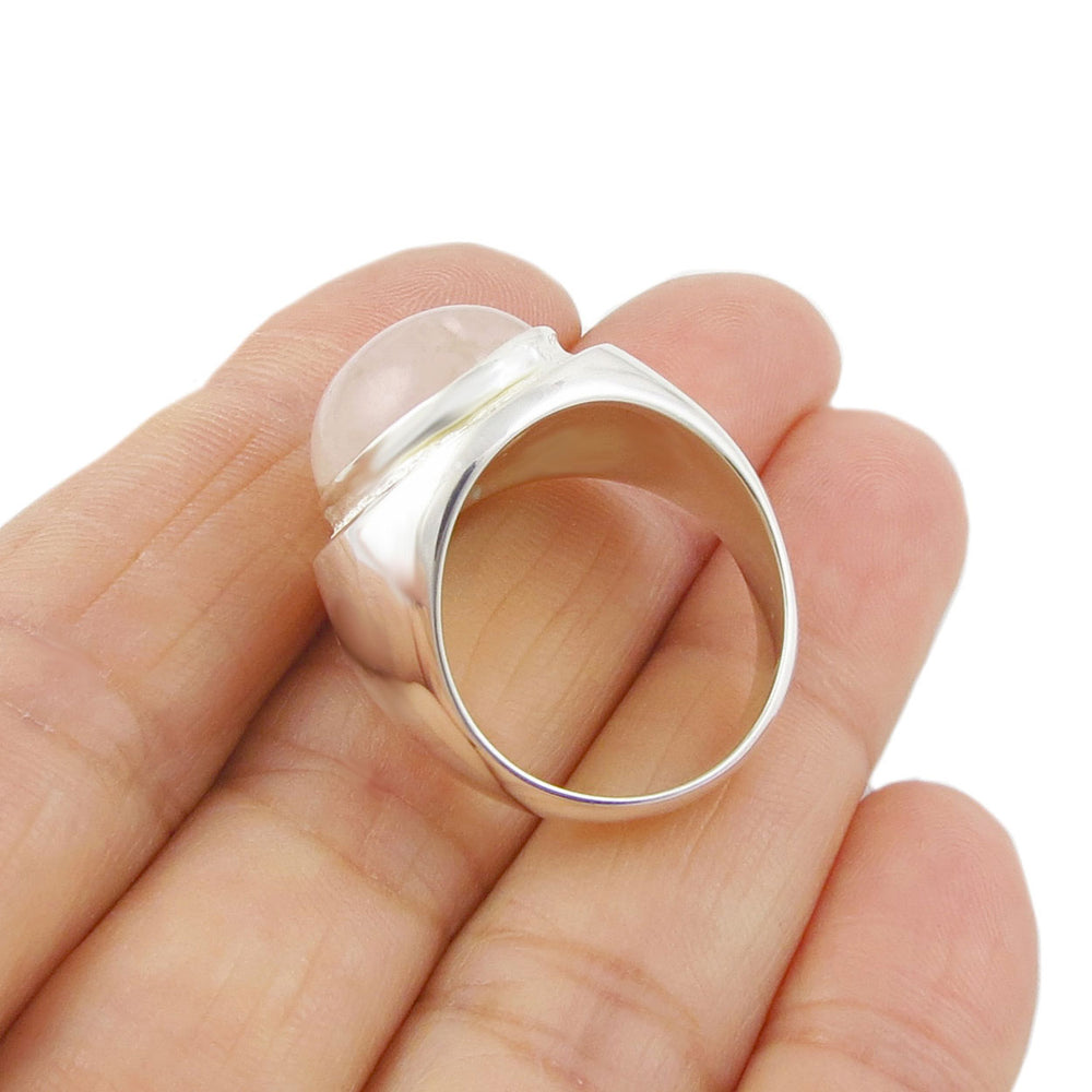 A chunky 925 sterling silver cocktail ring with a rose quartz gemstone held in a woman's hand. 