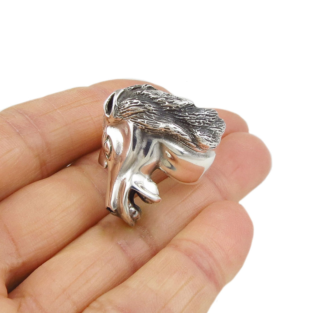A large sterling 925 silver cocktail ring in the shape of a horse head held in a woman's hand on a white background. 