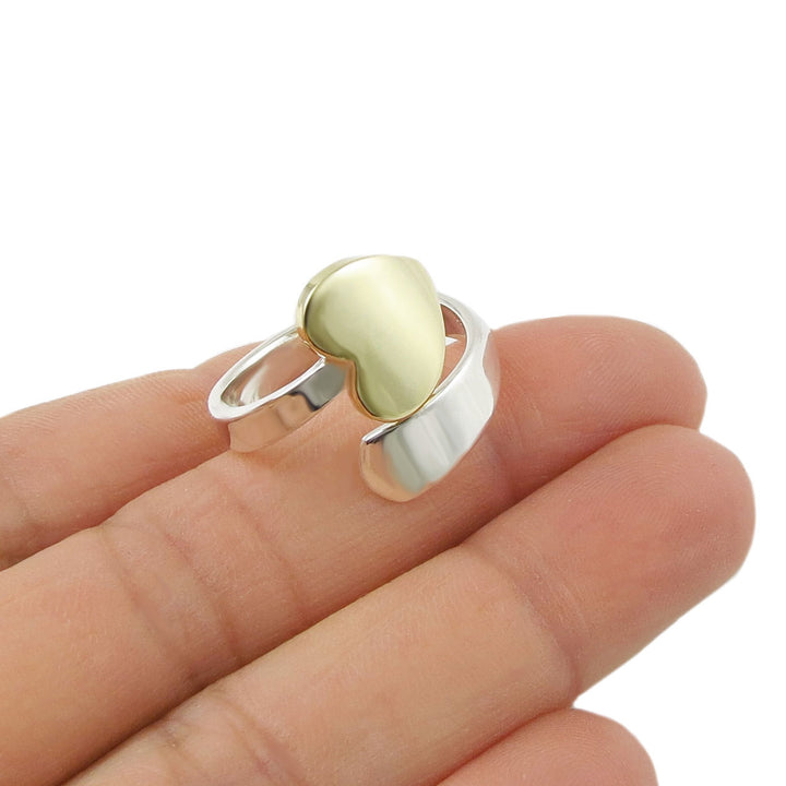 Gold heart and 925 sterling silver spiral two tone ring on a hand against a white background