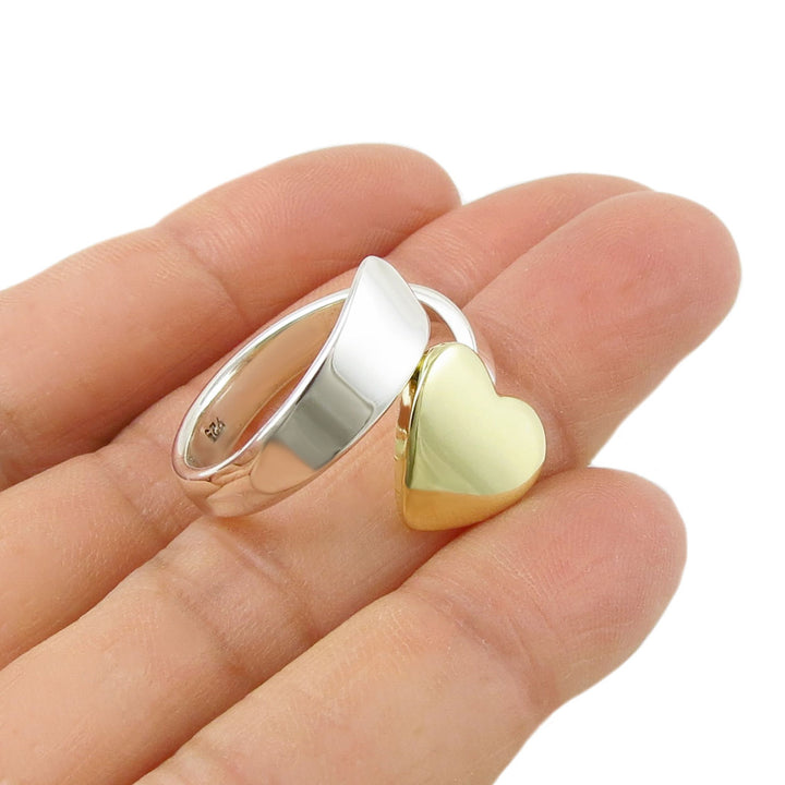 Gold heart-shaped accent on a 925 sterling silver spiral ring on a hand with a white background