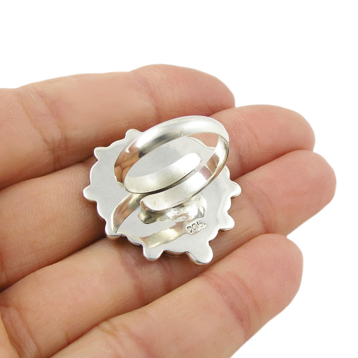 The reverse of a artisan handcrafted silver ring showing an adjustable size spiral shank and held in a person's hand. 