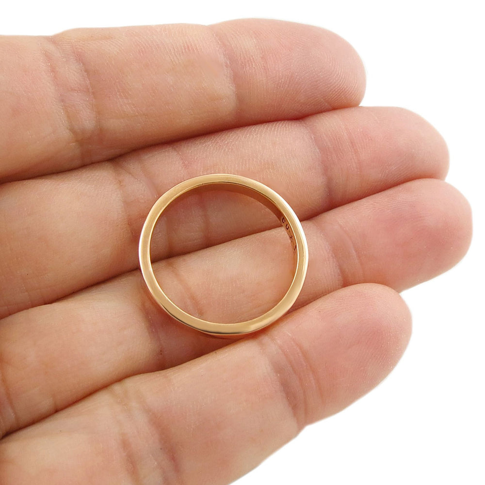 A solid polished copper ring jewellery held in a person's hand. 