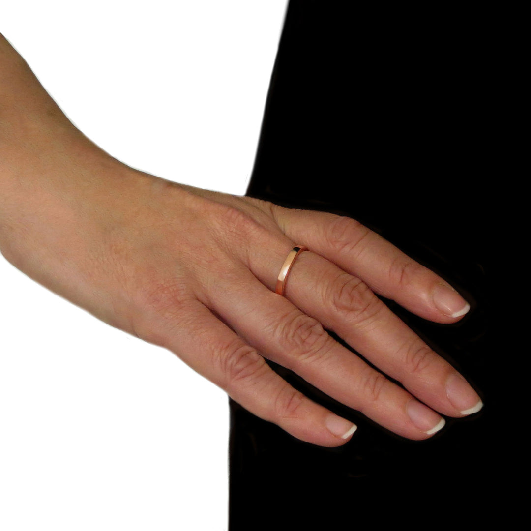 Woman's hand wearing a copper ring on a black and white background