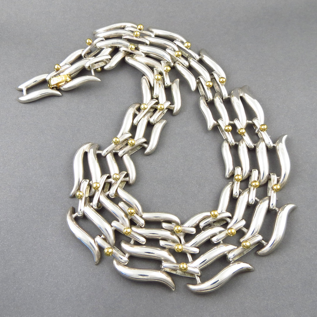 A large statement sterling 925 Silver Tane collar necklace with gold accents on a gray background