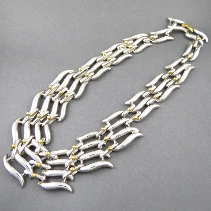 A chunky vintage Tane Mexican 925 sterling Silver necklace with gold accents on a gray background