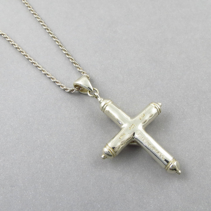 A large sterling 925 Silver cross pendant on a rope chain upside down to show the Mexican Sergio Bustamente siganture and hallmark against a gray background