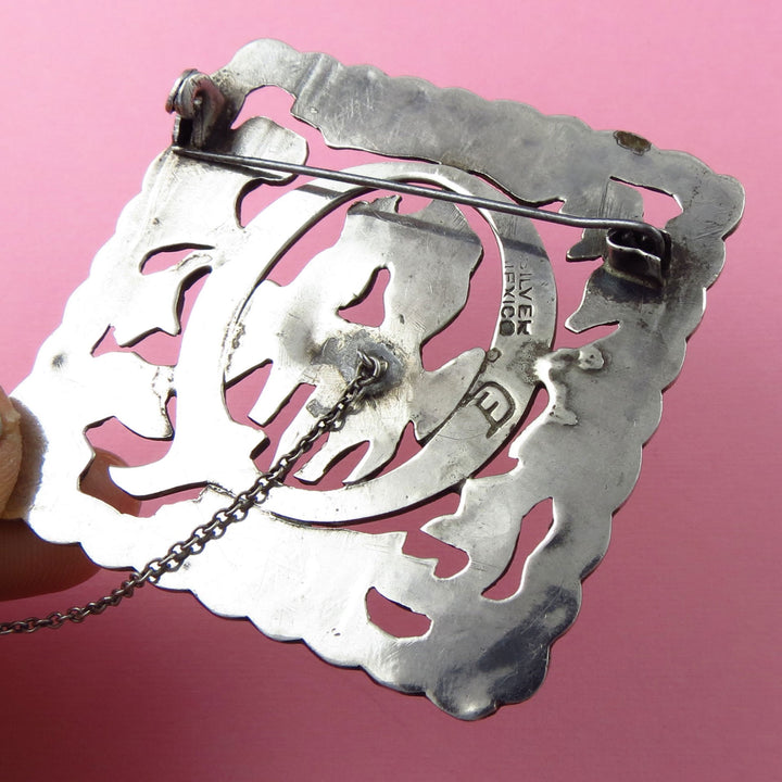 Sterling 925 Silver Fred Davis Mexico brooch with intricate design on a pink background