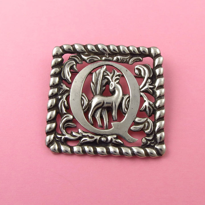 Antique Mexican Fred Davis design sterling 925 Silver brooch with a deer design and letter Q on a pink background