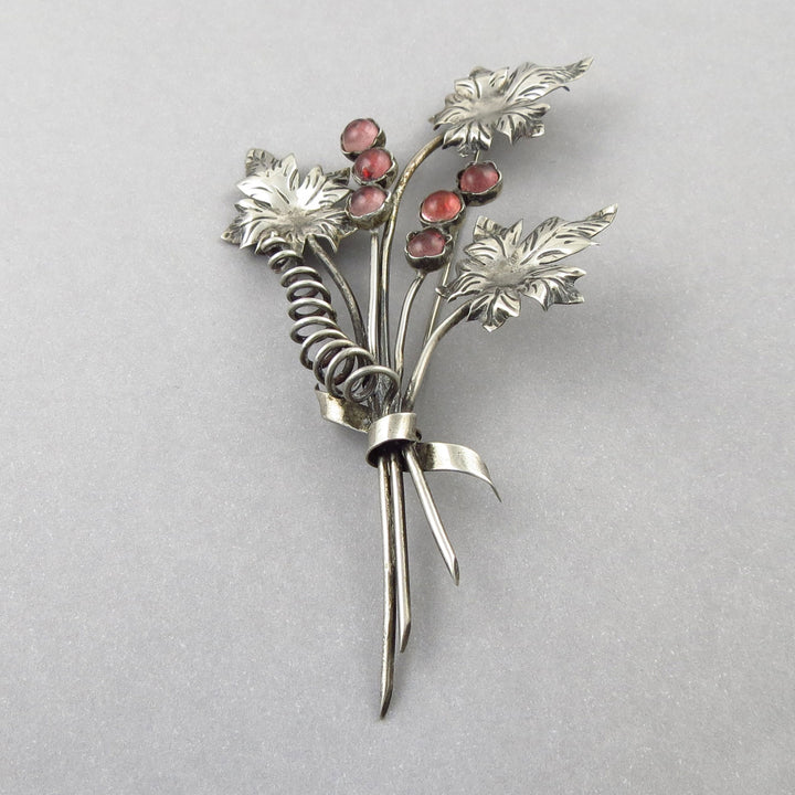 Vintage Mexican 925 silver bouquet of flowers brooch with pink gemstones on a gray background