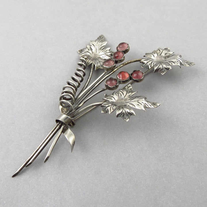 Mexican 925 Silver vintage brooch pin with floral design and pink gemstones on a gray background