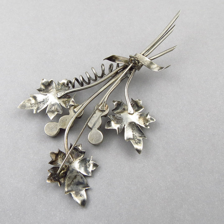 A large vintge 925 sterling silver leaf and flowers brooch upsside down on a gray background