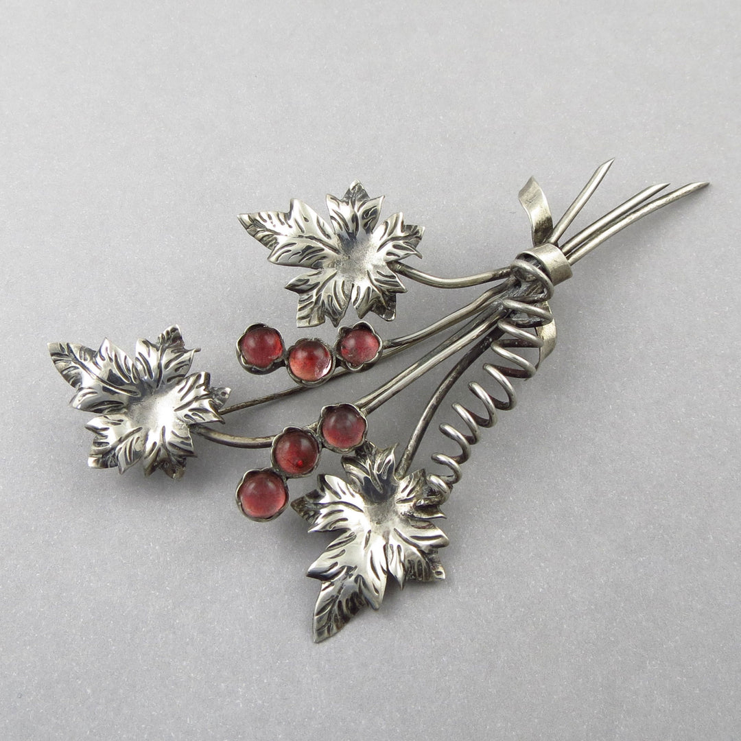 Mexican 925 Silver brooch with leaf designs and pink gemstones on a light gray background