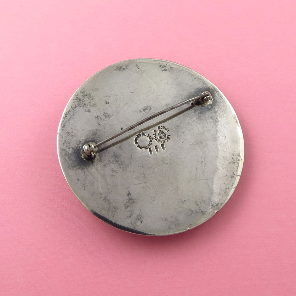Large Los Castillo sterling Silver brooch upside down to show the Mexican hallmark on a pink background