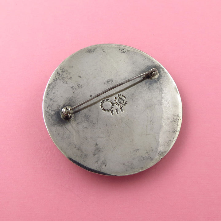 Large Los Castillo sterling Silver brooch upside down to show the Mexican hallmark on a pink background
