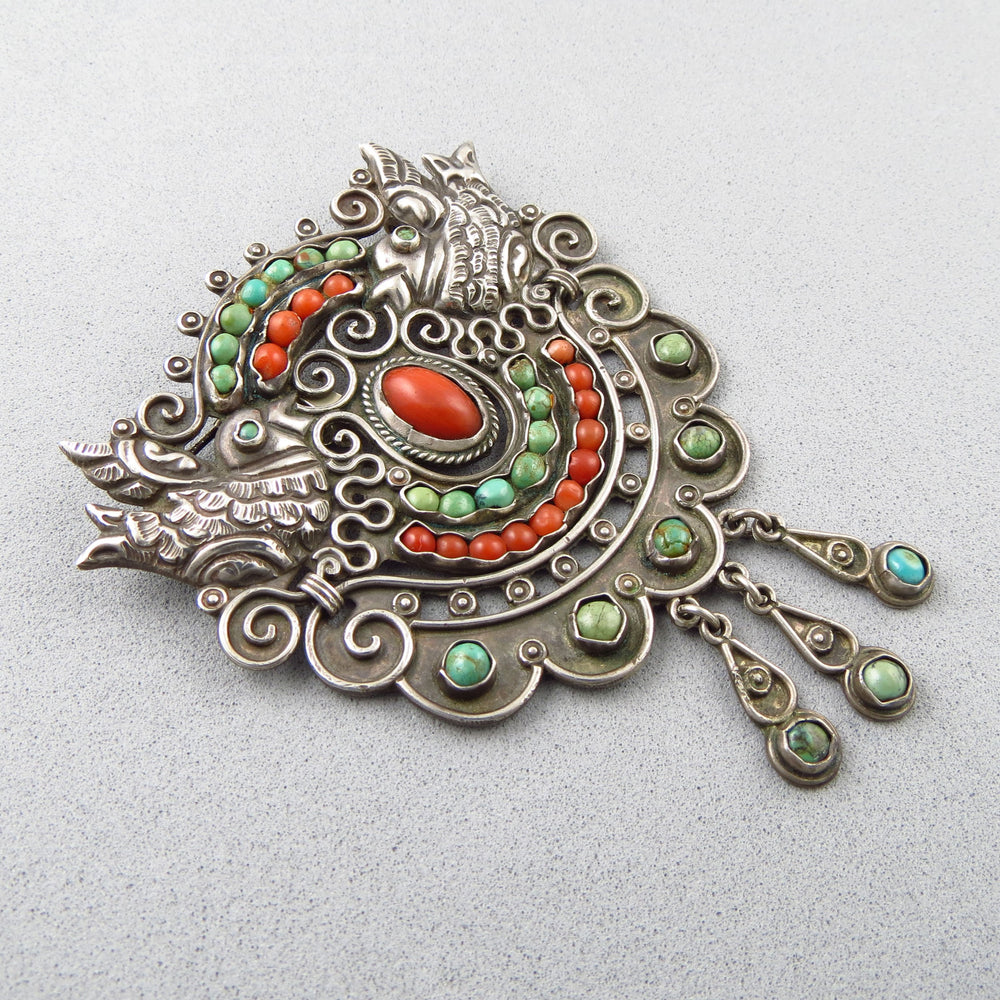 Large vintage Taxco Mexican 925 Sterling silver MATL ornate silver brooch with coral red and green turquoise gemstones on a light gray background