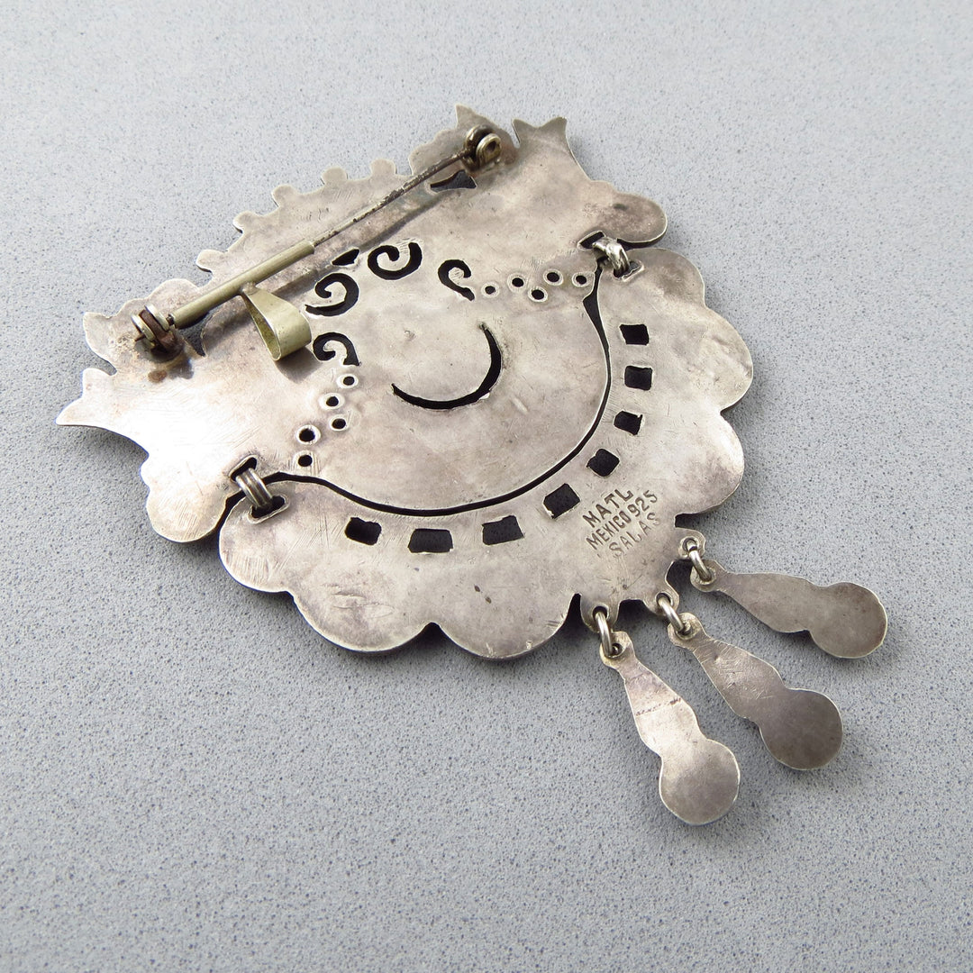 The reverse of a large Mexican 925 sterling silver pendant/brooch with decorative elements and the hallmark MATL Mexico 925 Salas on a gray background