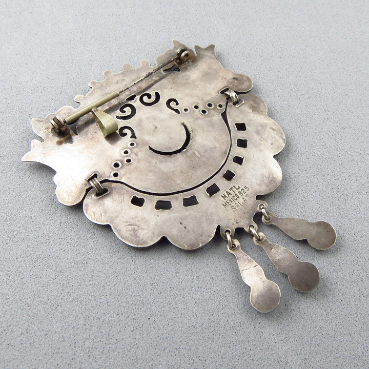 The reverse of a large Mexican 925 sterling silver pendant/brooch with decorative elements and the hallmark MATL Mexico 925 Salas on a gray background