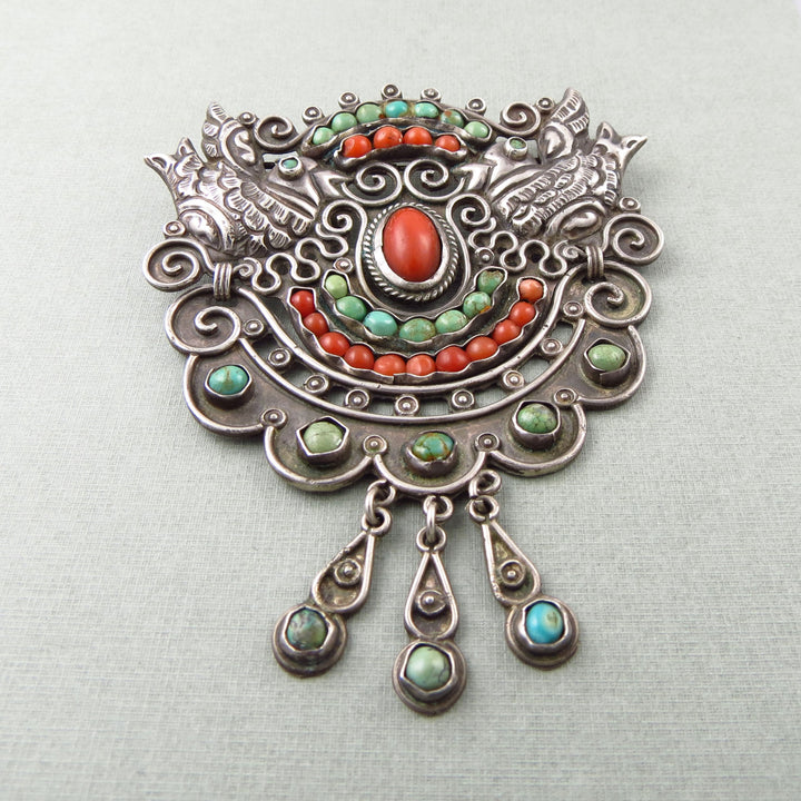 Vintage Matile Poulat MATL decorative Mexican 925 silver brooch with coral red and green turquoise gemstones on a light gray background