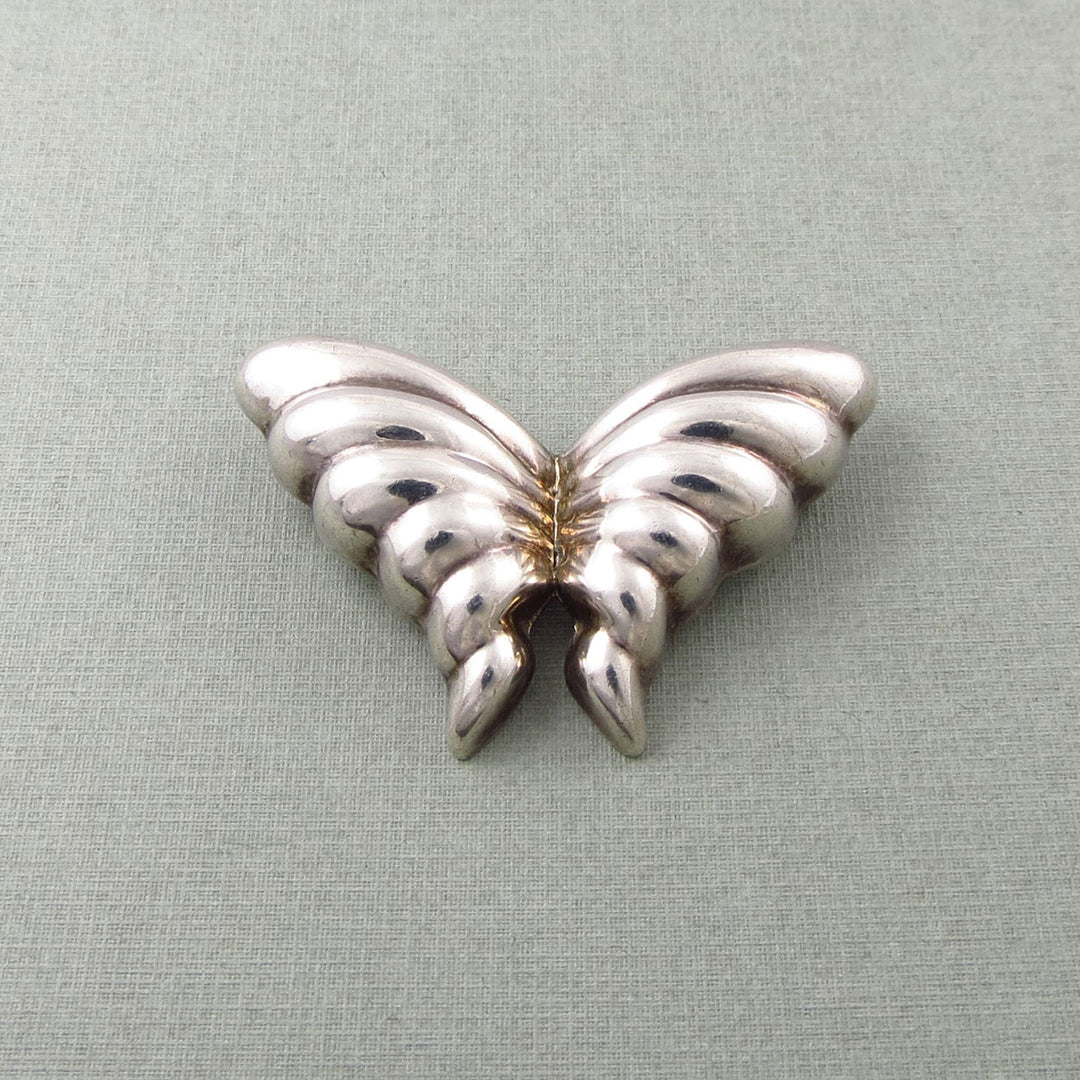 Silver butterfly-shaped Tiffany & co sterling silver brooch on a light gray background
