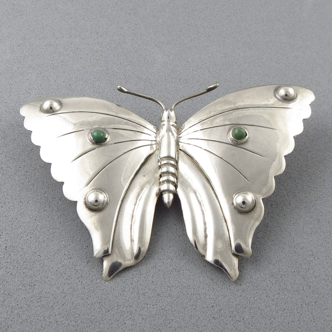 Vintage Monarch Butterfly 925 Silver brooch with green turquoise cabochons on a gray background