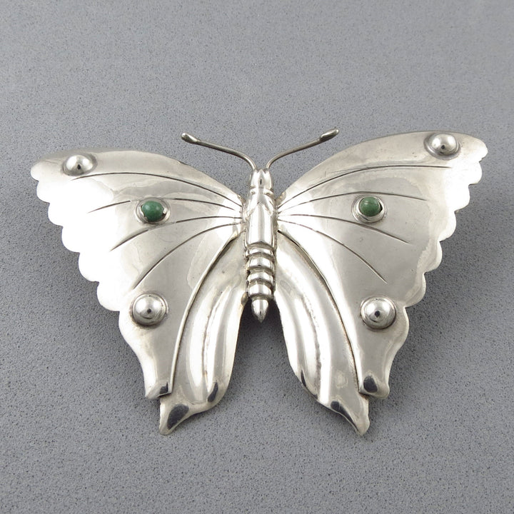 Vintage Monarch Butterfly 925 Silver brooch with green turquoise cabochons on a gray background