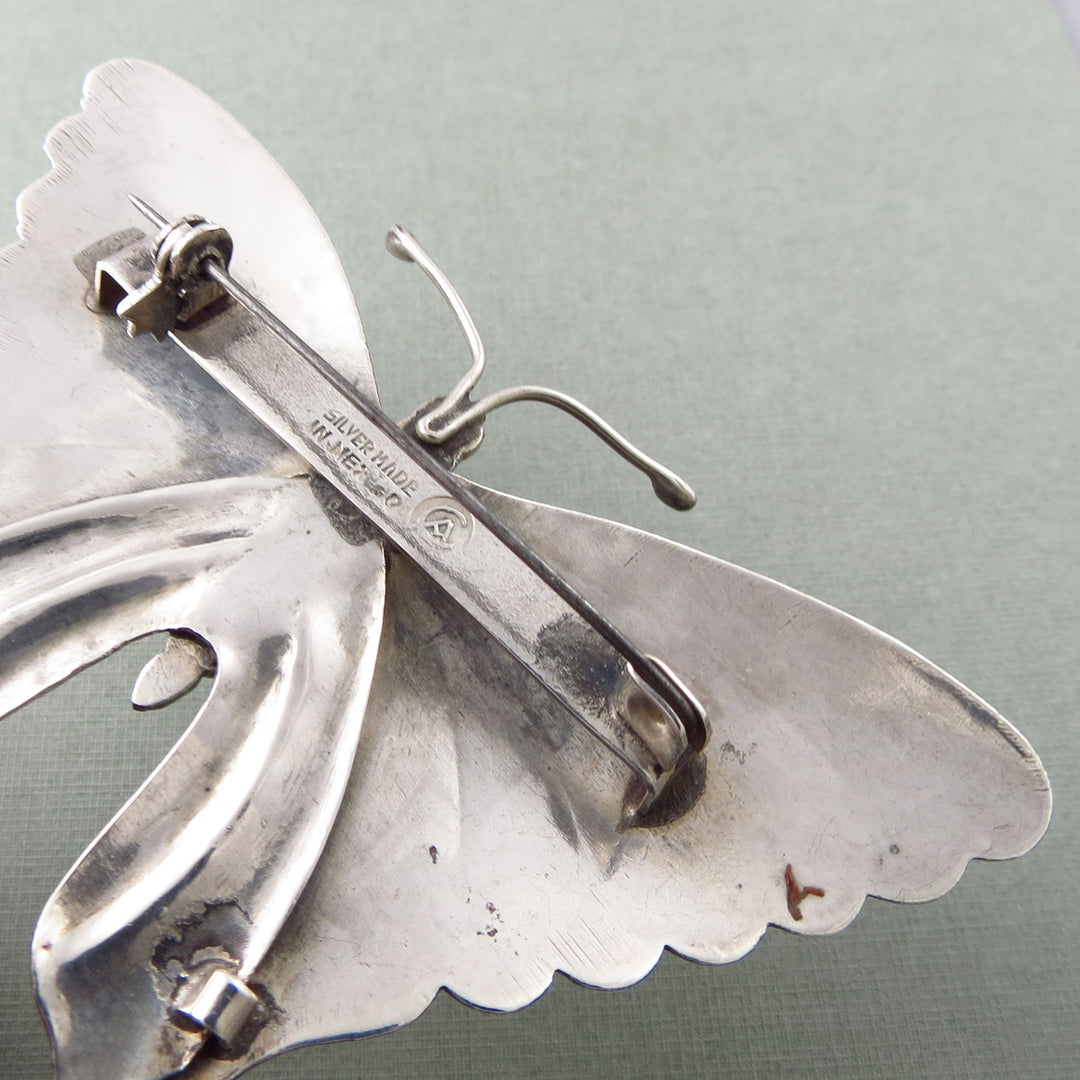 Close-up of the reverse of a handmade vintage Mexican monarch butterfly brooch in 925 sterling silver on a light gray background