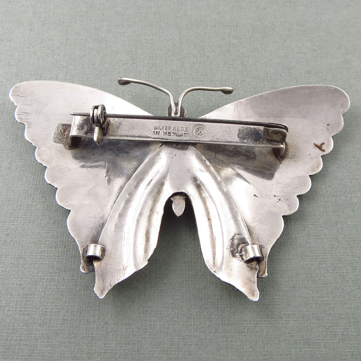 Vintage 925 sterling silver monarch butterfly brooch upside down on a grey background showing the Taxco silversmith hallmark