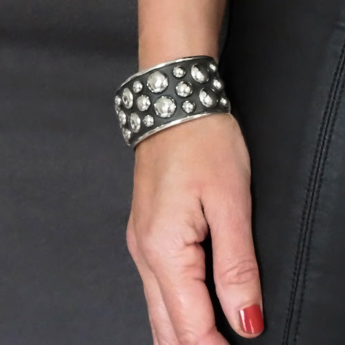 A bold sterling silver bead bracelet on a hand against a dark background. 