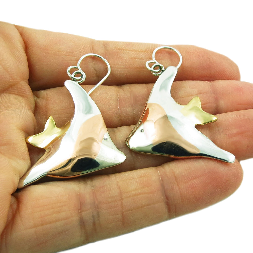 Large mixed metal angelfish earrings held in a person's hand. 