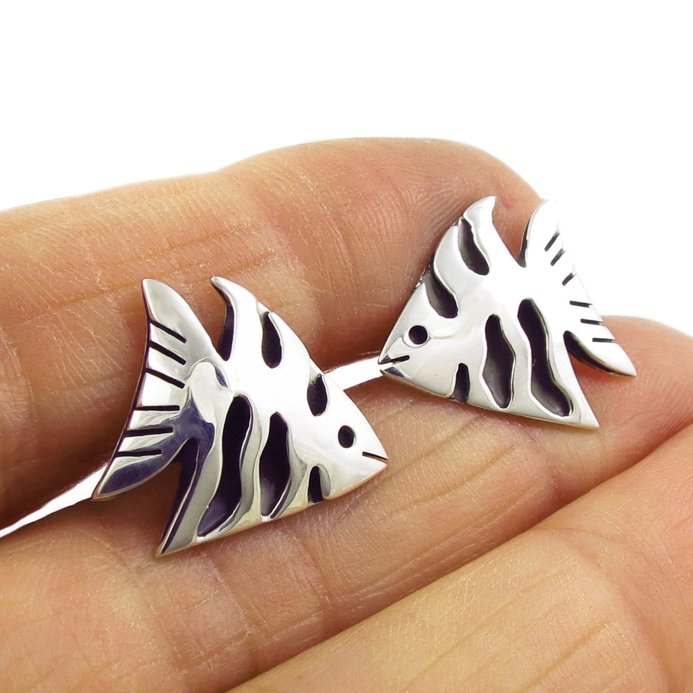 Large sterling 925 silver angelfish stud earrings held in a woman's hand