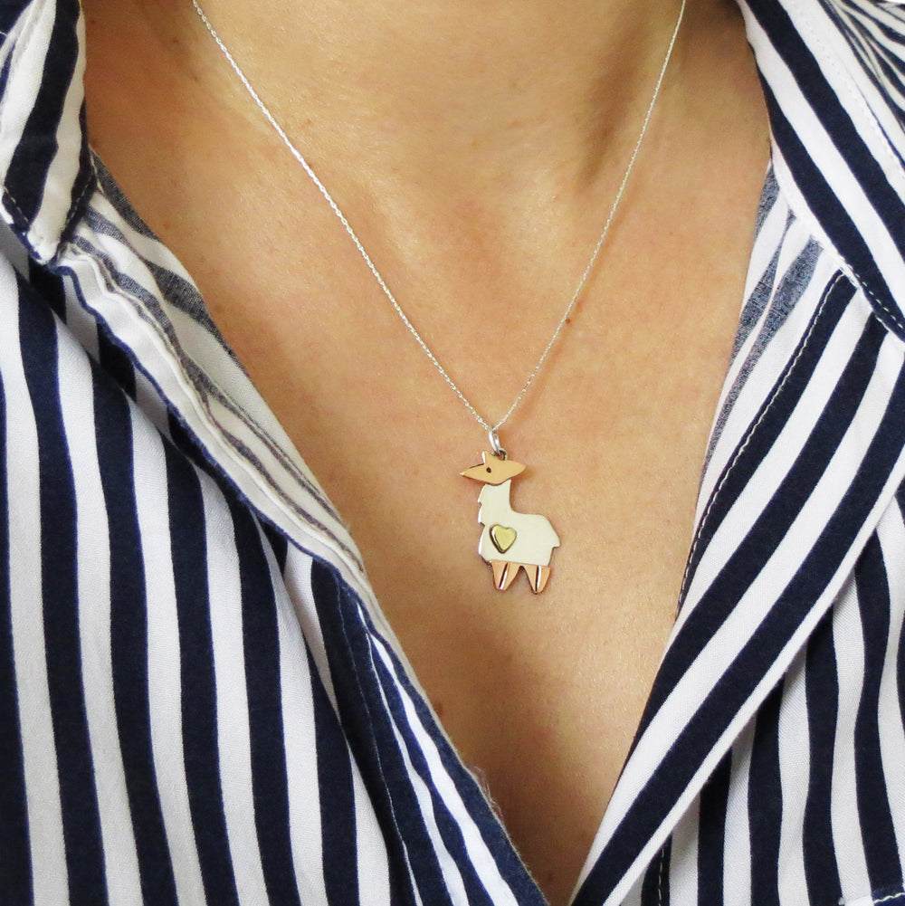 Mixed metal 925 silver and copper llama animal pendant and chain necklace worn by a woman in a blue striped blouse.