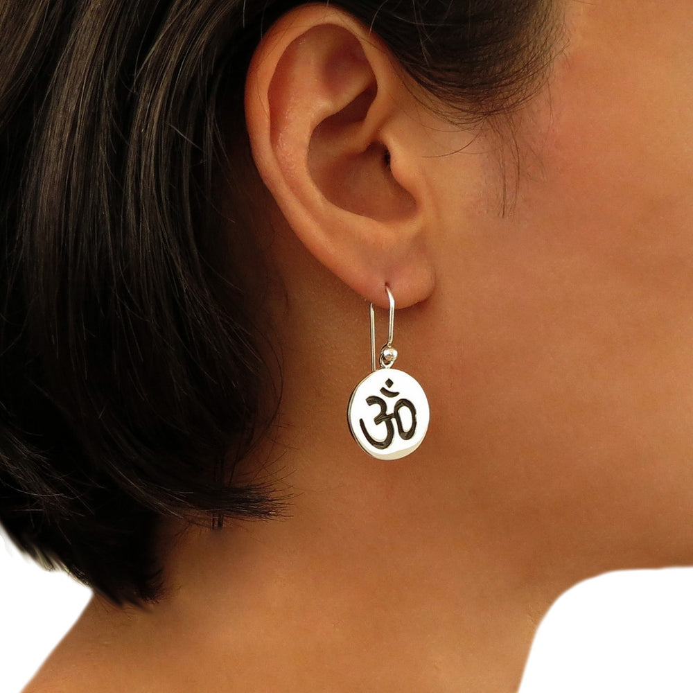 Large 925 silver disc earring with OM prayer symbol worn by a woman with dark hair