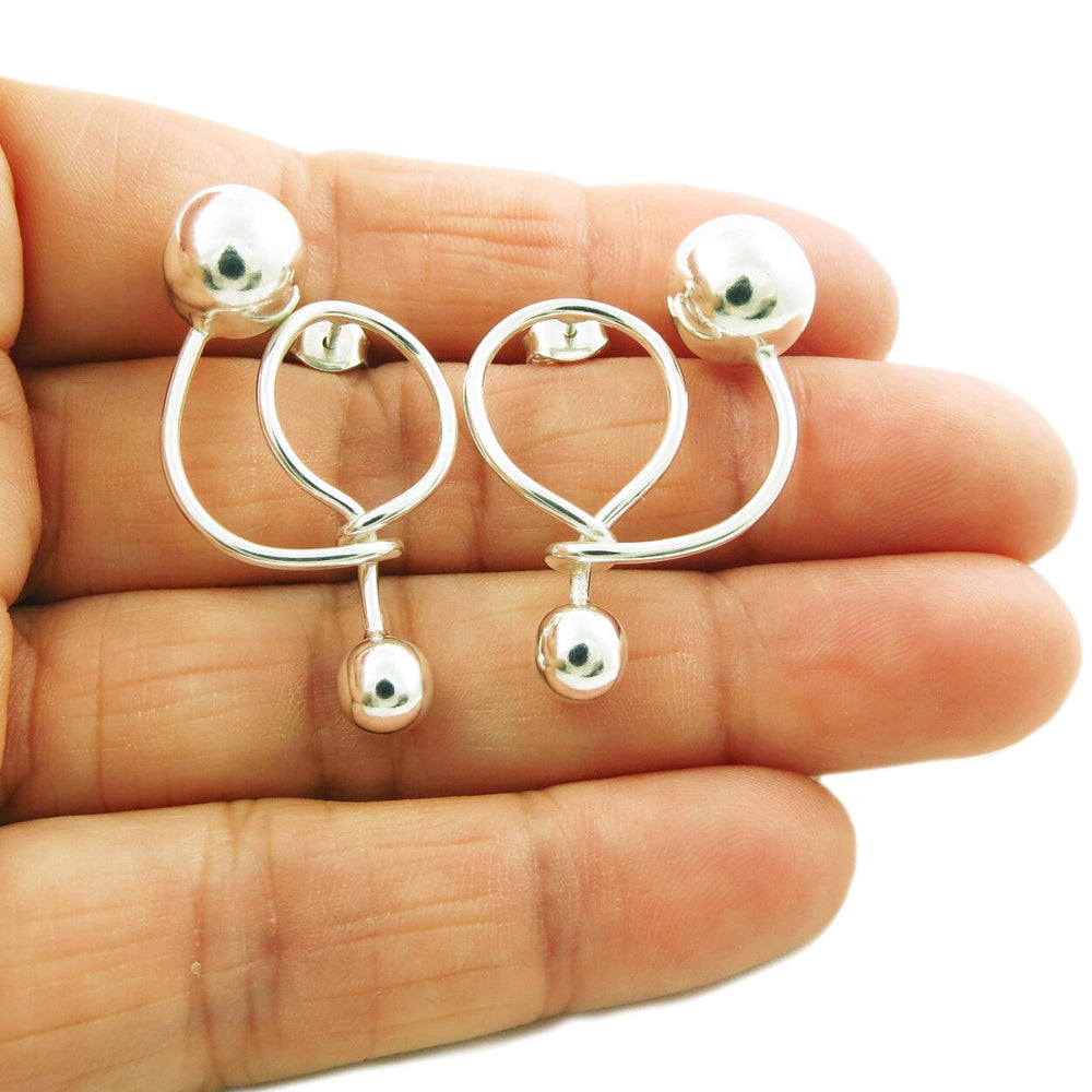 Unique spiral and ball bead modern sterling silver earrings held in a person's hand. 