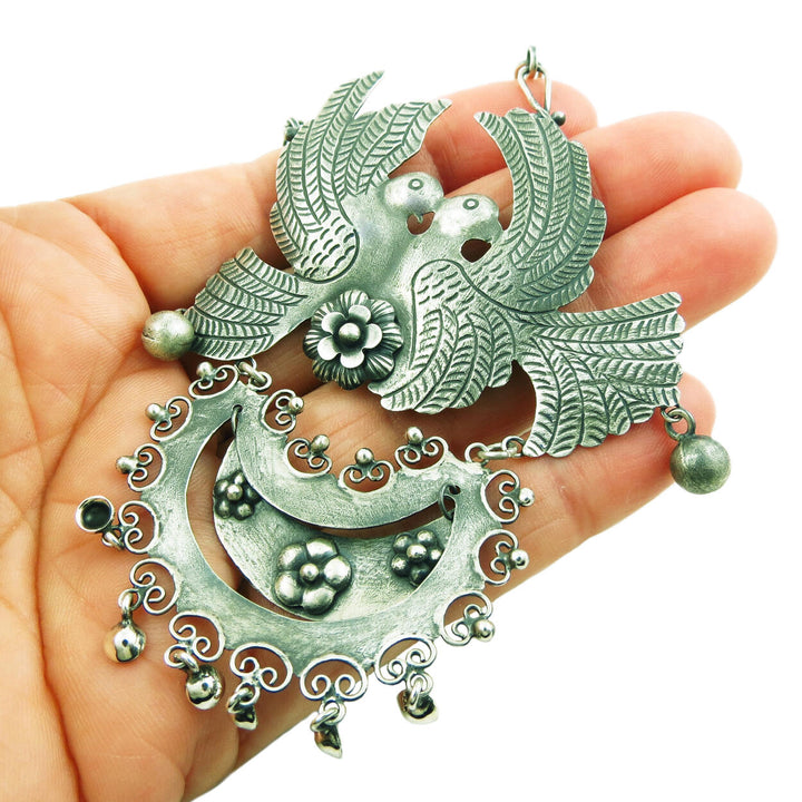Large antiqued 925 sterling silver Mexican lovebird necklace held in a woman's hand