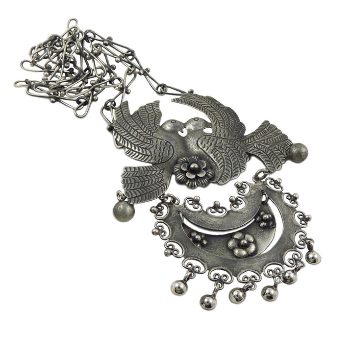 A large Mexican 925 sterling silver lovebird and flower statement pendant and chain necklace on a white background. 