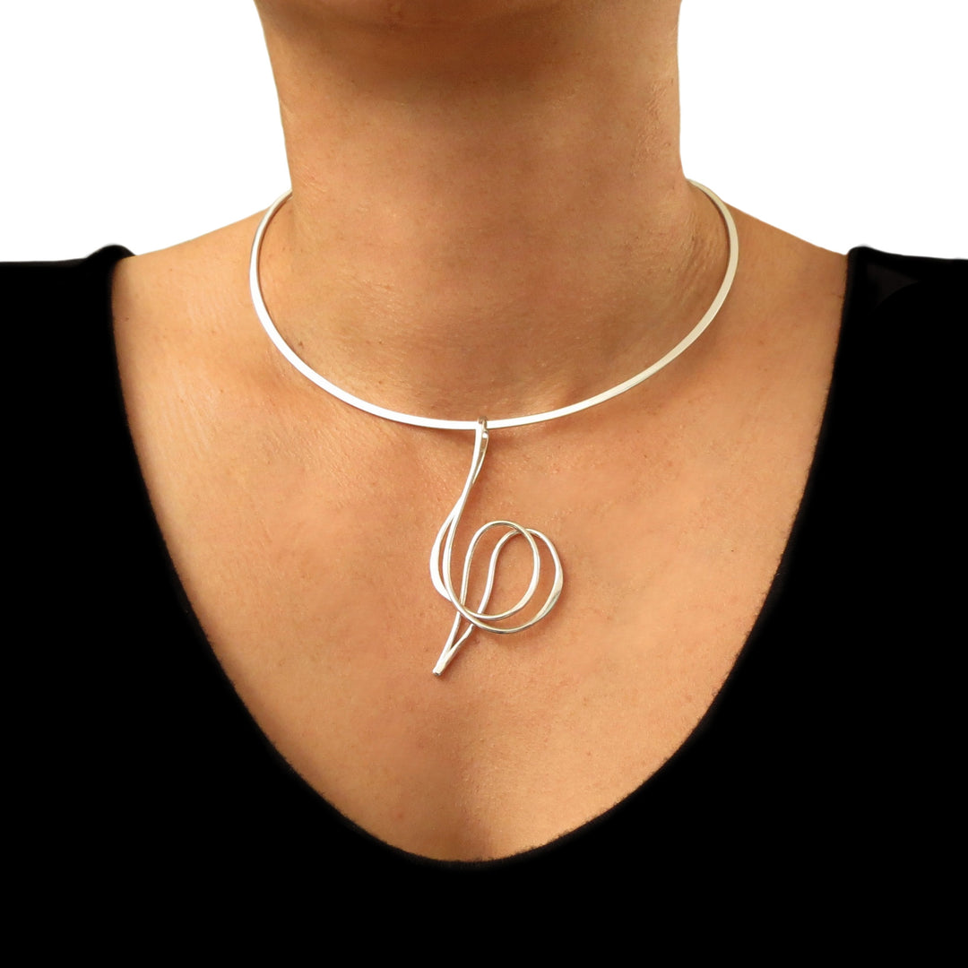 A woman wearing a spiral silver pendant on a silver choker 
