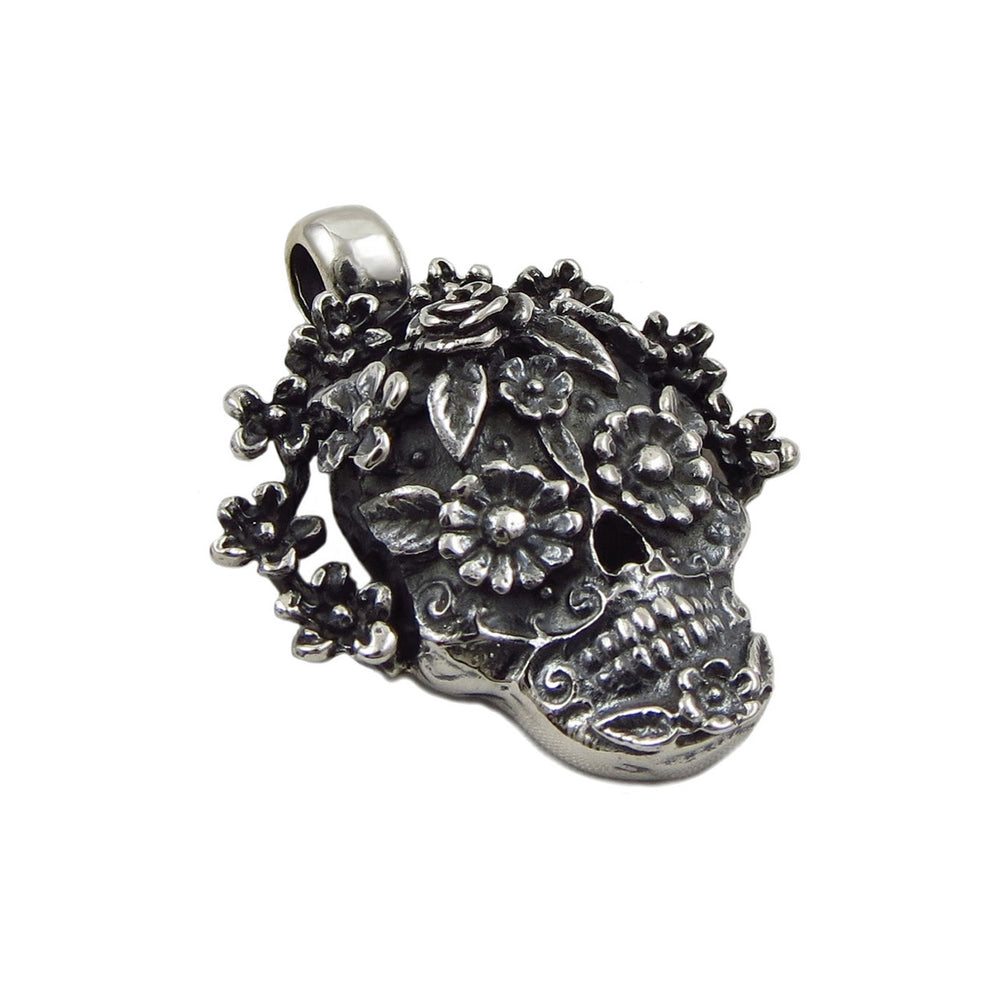 A mexican day of the dead sugar skull pendant with flowers on a white background. 
