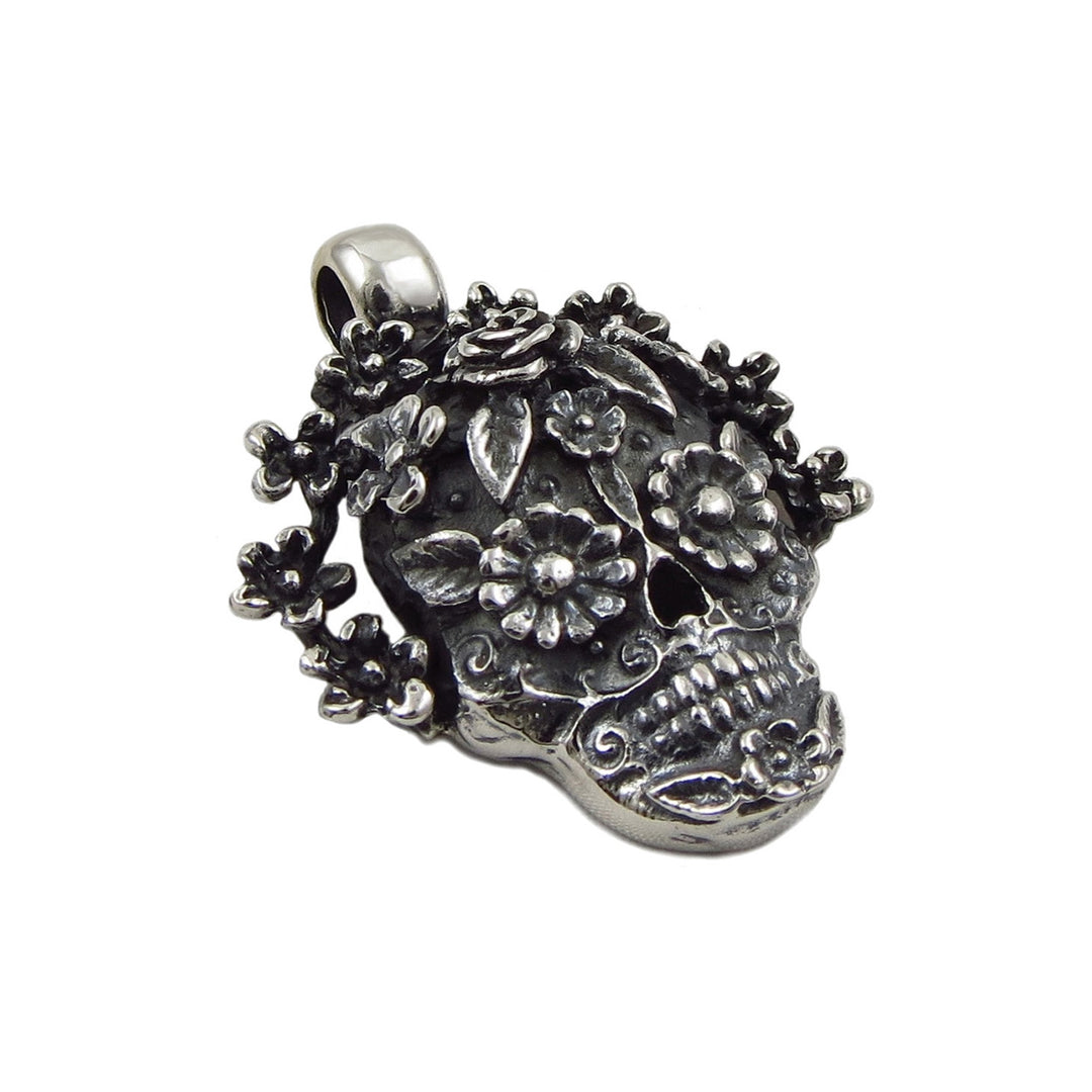 A mexican day of the dead sugar skull pendant with flowers on a white background. 