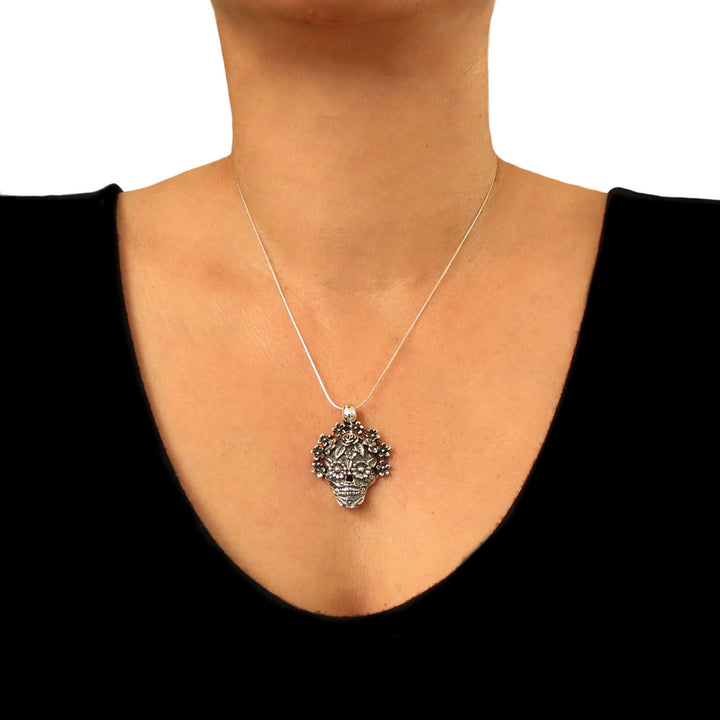 A woman in a black top wearing a Mexican day of the dead usgar skull pendant and chain necklace. 