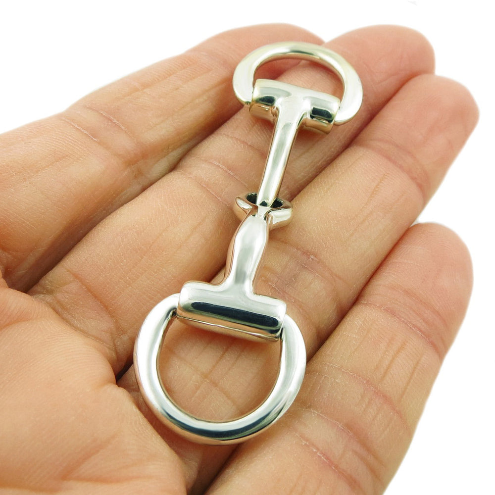 A large equestrian horsebit snaffle pendant in solid UK sterling 925 silver held in a person's hand