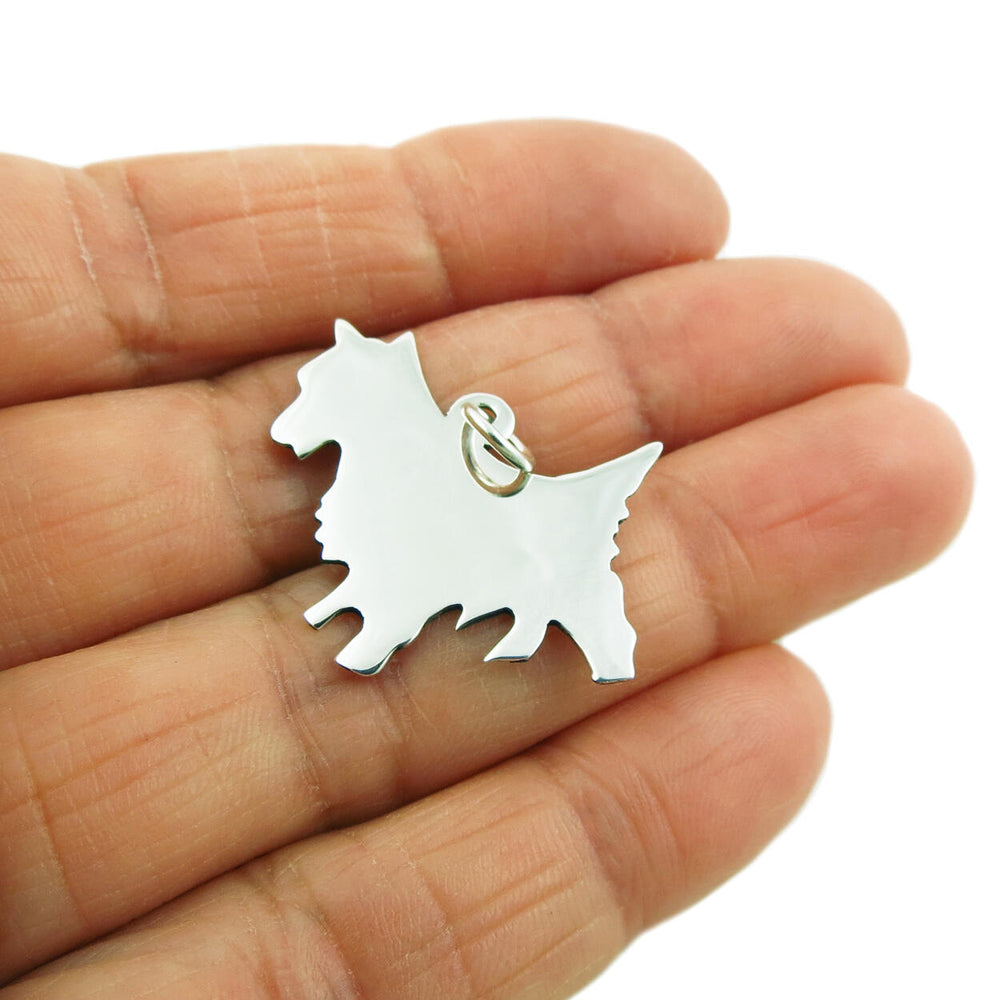 Sterling 925 silver terrier dog pendant jewellery held in a woman's hand on a plain background. 