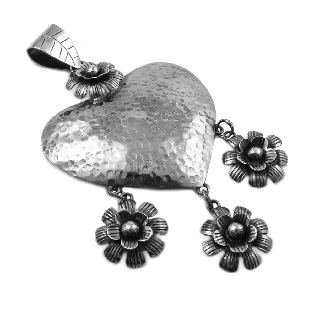 A large Mexican sterling 925 silver love heart pendant jewellery for women on a plain background. 