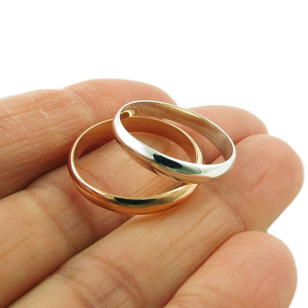 Two stackable rings made of silver and copper held in a person's hand, one ring is silver and the other is copper.