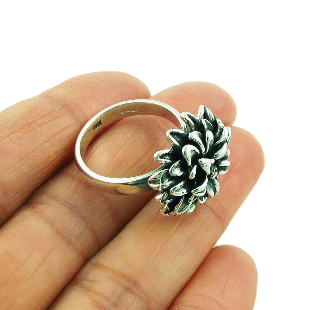 Large UK hallmarked silver flower ring held in a hand.
